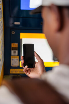 Person using phone at a public transport ticket machine.