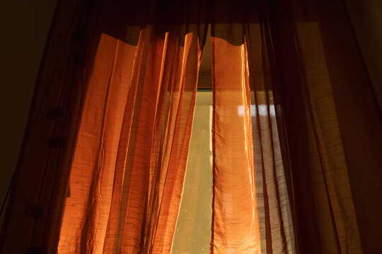 Golden Sunlight Filters Through Sheer Orange Curtains in a Cozy Room