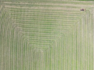 Aerial view of a tractor preparing hay in the field for making straw bales - Vue a&eacute;rienne d'un tracteur pr&eacute;parant le foin dans le champ pour la confection des bottes de paille
