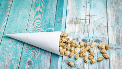 Boiled peanuts wrapped in cone-shaped paper on a rustic table