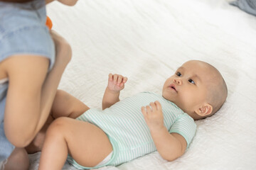 Asian mother bonding with her baby on the bed, showing love, happiness and parent child connection. Ideal for motherhood, child care, baby care, and family lifestyle concepts.