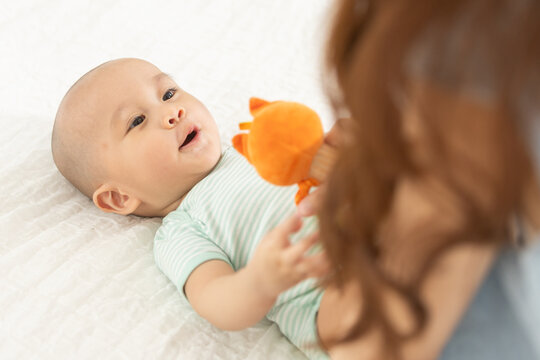 Asian mother bonding with her baby on the bed, showing love, happiness and parent child connection. Ideal for motherhood, child care, baby care, and family lifestyle concepts.