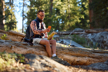 Tourist relaxes on a downed tree trunk