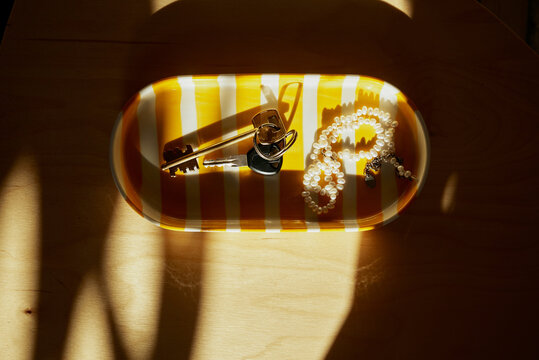 Keys and pearl necklace on a striped tray
