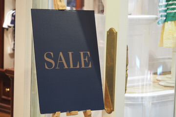 Sale sign in a boutique enticing shoppers in a busy store