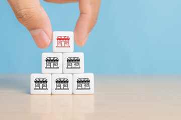 Hand choose dice stack in pyramid with franchise business store icon for franchising to growth branch expansion and business banking loan.