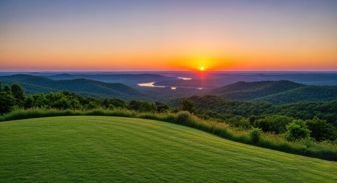 Sunrise over a lush green landscape with rolling hills and distant mountains in the distance.