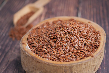 Brown flaxseeds in a wooden bowl on a rustic table