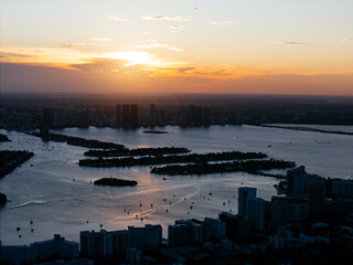 Fototapeta premium Aerial view of Biscayne Bay and Miami skyline at sunset with small islands and boats in the water. g.