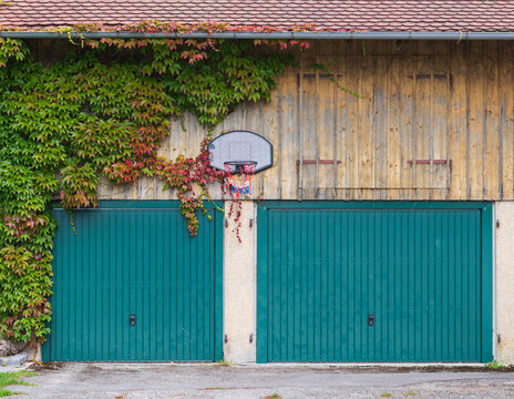 Ivy Covered Garage with Basketball Hoop and Green Doors