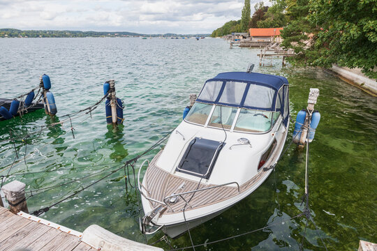 White Motorboat Docked on Peaceful Lake Shore