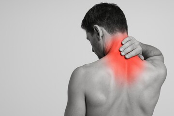 horizontal photo of a shirtless man seen from behind holding his neck, with a strong red overlay emphasizing pain and muscle tension, suitable for medical, physiotherapy, chiropractic, sports injury