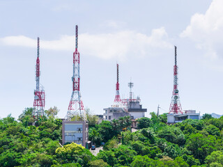 Communication towers on green hilltop against blue sky
