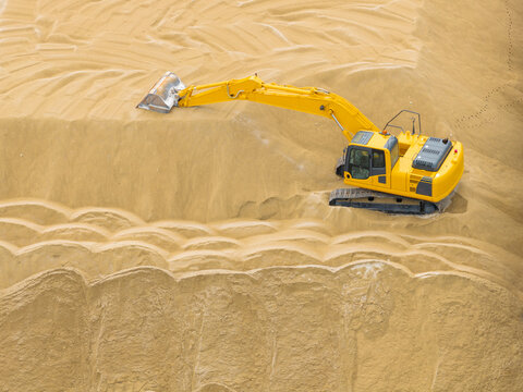 Yellow Excavator on a Large Sand or Gravel Pile