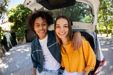 Portrait of couple sitting on car trunk smiling at camera. Fisheye.