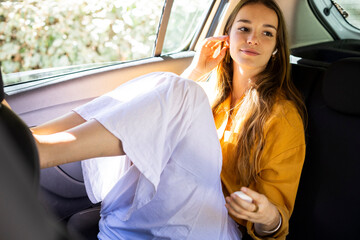 Girl in back seat of car using earbuds smiling