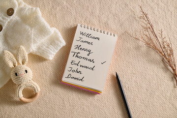 Baby name selection with a notepad, pen, and a cute bunny rattle.