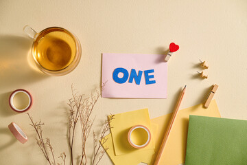 Creative flat lay composition with the word ONE on a pink paper.