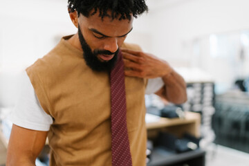 Black Man is Adjusting Tie and Checking Colour in Men's Clothing Store