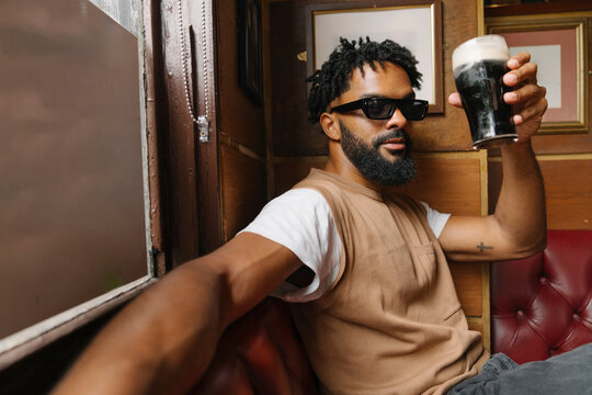 Handsome Man Enjoys Stout Beer Inside a Lively Irish Pub