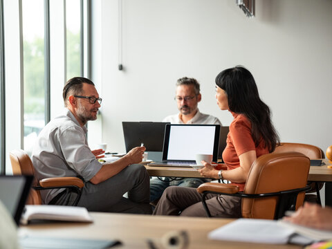Three People Collaborating in the Modern Office with Laptops