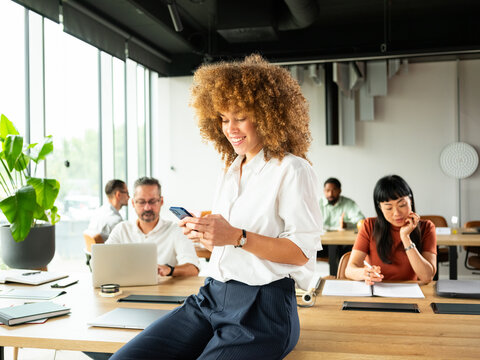 Confident Woman Using Phone in Bright Modern Office 