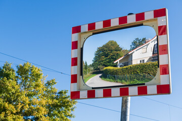 Convex Safety Mirror Reflects Rural Road and House
