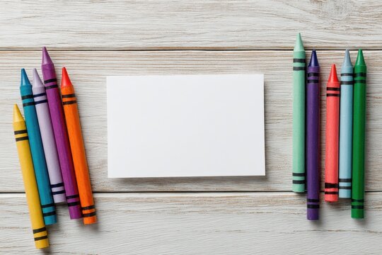 Colorful crayons surrounding a blank white card on wood
