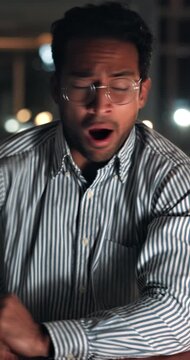 Tired, man and wake up in office at night with glasses, editing break and overworked on story. Publishing agency, exhausted journalist and yawn with bokeh from low energy, narcolepsy or news deadline