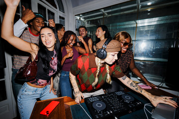 Young diverse friends enjoying party with dj playing music