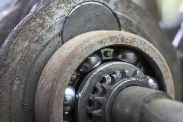 Industrial close up of rusty metal ball bearing and gear. This old, dirty machinery part shows significant wear and tear, representing sense of decay and disrepair