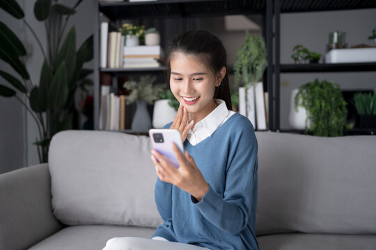 Asian woman using voice assistant on smartphone at home conversation with online assistant Voice chat bot conversational AI Modern Technologies