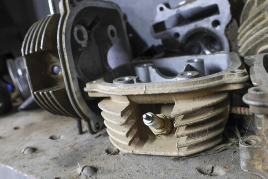 Close up view of disassembled engine block with cylinder head on workbench in workshop. dirty metallic part shows process of mechanical repair or maintenance