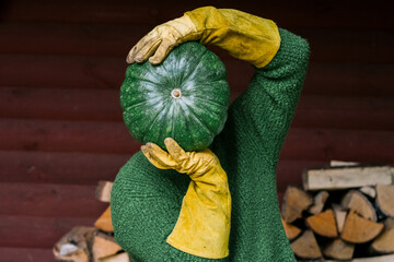 A man holds a large green pumpkin in front of him