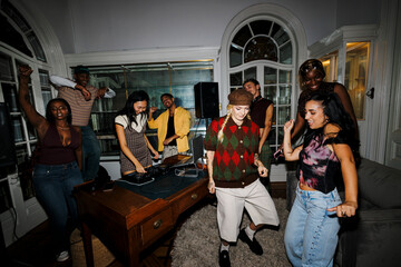 Diverse young adults enjoying a house party with a dj