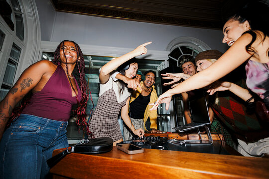 Young diverse friends dancing at a house party with dj