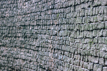 Stone wall made of uneven gray blocks creating a rough natural texture in close up view