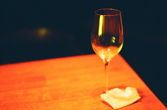 Glowing Wine Glass on a Wooden Table in a Dimly Lit Space