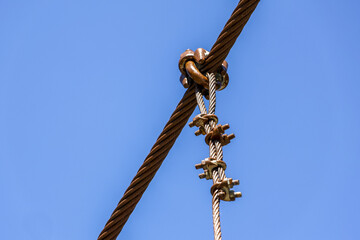 Close up of strong steel cable with wire rope clip and connection against clear blue sky. industrial detail conveys strength, security, and connection for construction