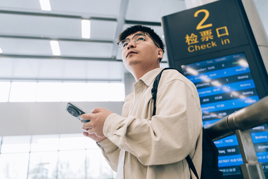 Asian man using mobile phone in train waiting room