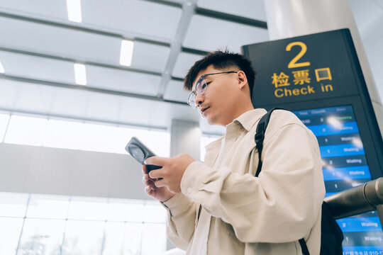 Asian man using mobile phone in train waiting room