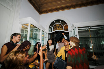 Diverse young adults enjoying house party, dancing and taking photos