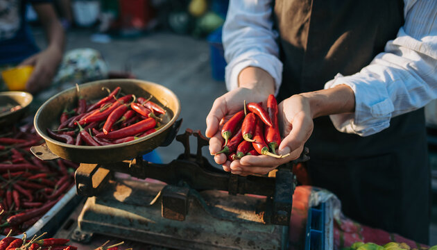 Vendor displaying fresh red chili peppers at an outdoor market. - Powered by Adobe
