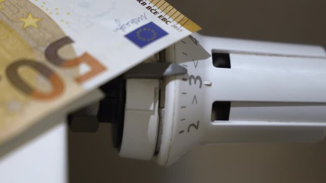 Fifty-euro banknote placed on a radiator thermostat, symbolizing rising heating expenses, energy prices and the financial burden of maintaining household warmth in winter.
