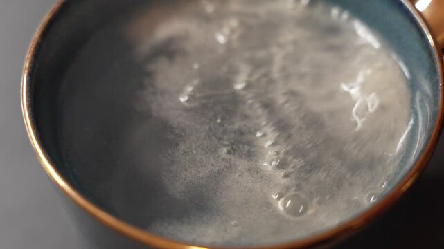 Close-up view of sparkling water bubbling intensely in a glass, showing active carbonation, rising bubbles and dynamic motion on the liquid surface.