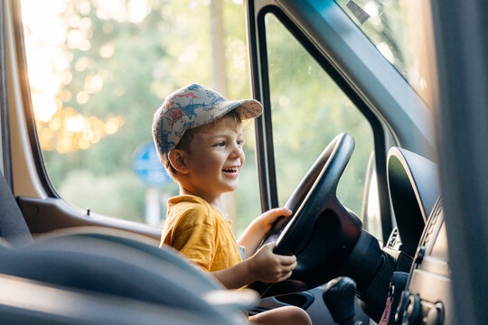 Happy boy pretending driving van on family adventure