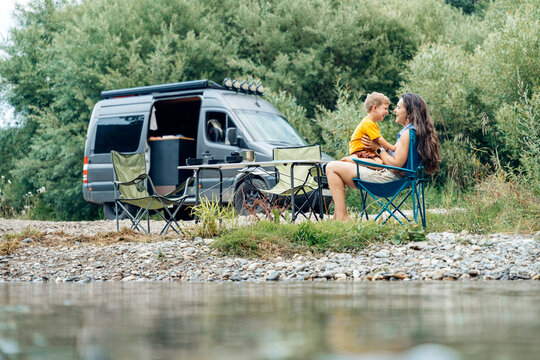Mother and son enjoying van life camping by river