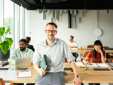 Confident Office Leader With Book and Folder In Modern Open Space