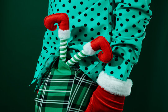 elf legs peek out of the pocket of the green plaid trousers of a man