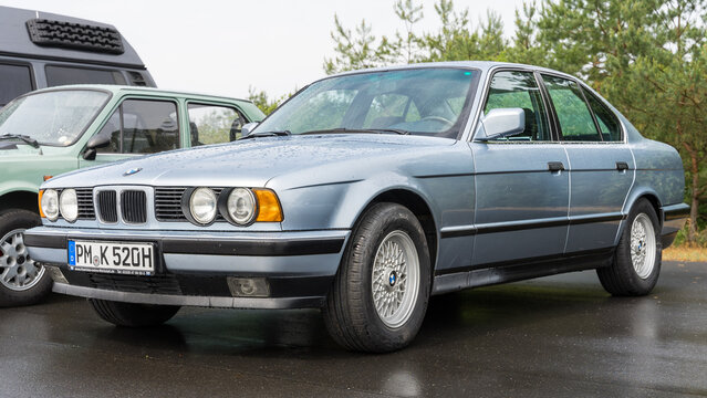 LINTHE, GERMANY - JUNE 08, 2025: The executive 4-door BMW 5 Series E34 classic sedan in blue color under rain. Die oldtimer show.